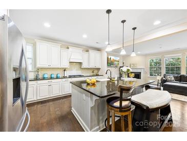 Bright eat-in kitchen with white cabinets, dark countertops and island with barstool seating at 11519 Sweet Birch Ln, Charlotte, NC 28278