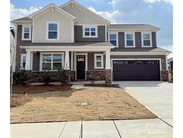 Charming two-story home boasts a stone-accented facade, covered porch, and an attached two-car garage at 1709 Honey Trl, Monroe, NC 28112