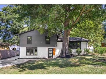 Stylish mid-century modern home with gray and white exterior, landscaping, and large tree at 3801 Woodleaf Rd, Charlotte, NC 28205