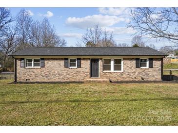 Brick ranch house with a landscaped lawn and dark-colored front door at 4804 Chapel Grove Rd, Gastonia, NC 28052