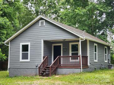 Gray house with brown porch and steps, surrounded by lush green trees at 1302 Brookdale St, Kannapolis, NC 28083