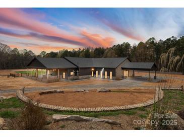Stunning home with a dusk sky, stone accents, covered parking, a horseshoe drive, and lush landscaping at 1565 Shinnville Rd, Cleveland, NC 27013