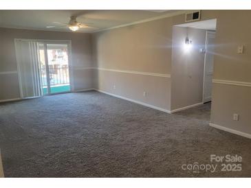 An open living room featuring neutral paint, carpet, and a sliding glass door leading to a balcony at 2121 Carriage Woods Ln, Kannapolis, NC 28081