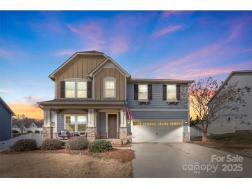 Two-story house with gray and beige siding, a brick front porch, and a two-car garage at 5055 Stonehill Ln, Matthews, NC 28104