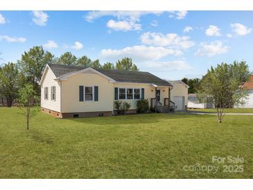 Charming yellow house with green lawn and a detached garage at 104 E Main St, Cleveland, NC 27013