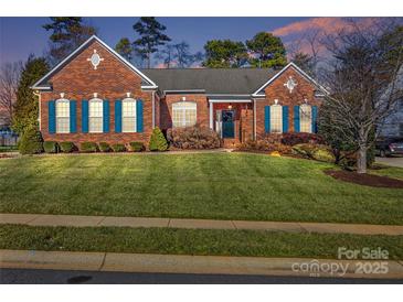 Brick ranch home with landscaped lawn and blue shutters at 1117 Butterburr Dr, Matthews, NC 28104