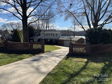 Brick ranch home with long driveway, brick wall, and mature trees at 273 Leeward Point Loop, Taylorsville, NC 28681