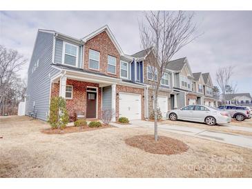 Two-story townhome with brick and siding exterior, two-car garage, and landscaping at 3936 Rothwood Ln, Harrisburg, NC 28075