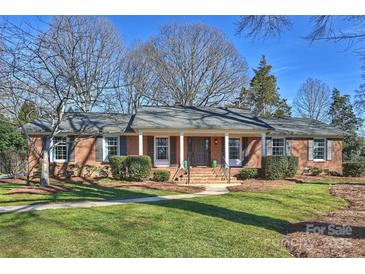 Brick ranch home with a covered porch, steps, and a well-manicured lawn at 6511 Newhall Rd, Charlotte, NC 28270