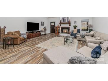 Spacious living room features a cozy fireplace, wood floors, and comfortable seating area at 1076 Furnace Rd, Iron Station, NC 28080