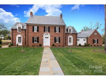 Charming brick home featuring a manicured lawn, stone walkway, and classic architectural details at 2400 Mecklenburg Ave, Charlotte, NC 28205