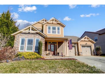 Two-story house with stone and shingle accents, two-car garage, and landscaped yard at 14818 Long Iron Dr, Huntersville, NC 28078