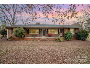 Charming single-story brick home with a cozy front porch and mature trees under a colorful sky at 3050 Wilkesboro Hwy, Statesville, NC 28625