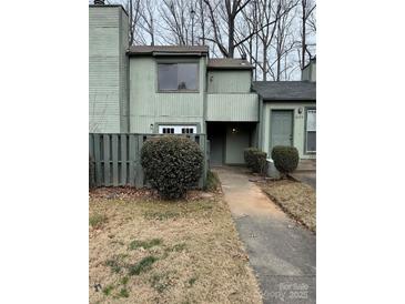 Exterior view of a green townhouse with a walkway and landscaping at 6126 Bent Tree Ct, Charlotte, NC 28212