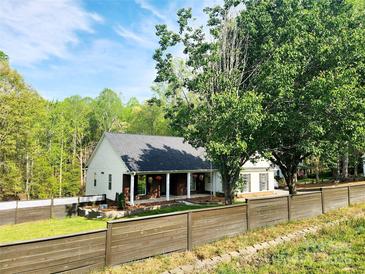 Charming single-story home featuring a welcoming front porch, mature trees, and a wooden fence surrounding the property at 888 Brevard Place Rd, Iron Station, NC 28080
