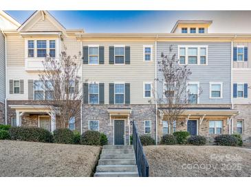 Two-story townhome with stone and siding exterior, landscaping, and a concrete walkway at 9115 Bluefield St, Charlotte, NC 28273