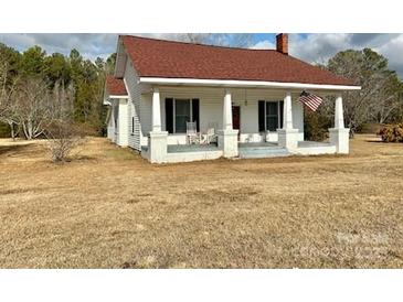 White house with red roof, front porch, and American flag at 6963 Kershaw Camden Hwy, Kershaw, SC 29067