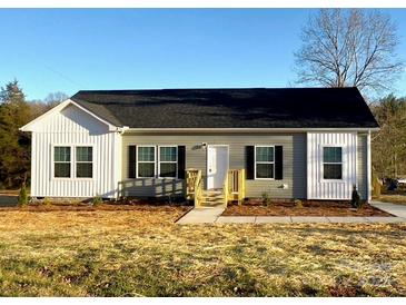 Charming home featuring gray siding, black shutters, complemented by a welcoming wooden porch and fresh landscaping at 823 Wellwood Ave, Statesville, NC 28677