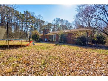 Expansive backyard with a trampoline, mature trees, and plenty of space for outdoor activities at 1900 E Dixon Blvd, Shelby, NC 28152