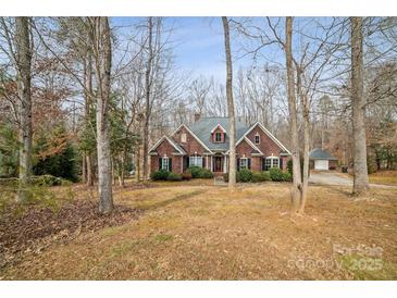 Charming red brick home featuring dormer windows and mature trees, with a detached garage at 2113 Sweet Clover Way, Denver, NC 28037