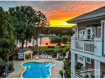 Community pool with lounge chairs, overlooking lake with sunset at 7844 Village Harbor Dr, Cornelius, NC 28031