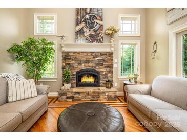 Cozy living room featuring a stone fireplace, hardwood floors, and ample natural light at 3196 Stonemill Path, Sherrills Ford, NC 28673