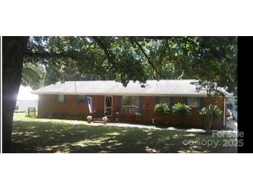 Charming single-story brick home with a well-manicured front lawn and mature shade trees at 504 Amon Ln, Pineville, NC 28134