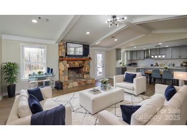 Inviting living room with a stone fireplace, wood floors, and an open floor plan to the modern kitchen at 6615 Love Mill Rd, Monroe, NC 28110