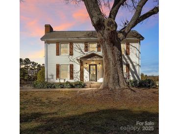 Two-story farmhouse with shutters, landscaping, and a large tree in the front yard at 3433 Grey Rd, Davidson, NC 28036