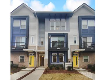 Modern three-story townhome with yellow door and gray siding at 2124 Electric Ln, Charlotte, NC 28205