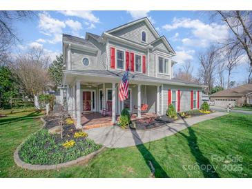 Charming two-story home with a covered front porch, American flag, and well-maintained landscaping at 10111 Grimsby Ct, Huntersville, NC 28078