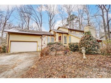 House exterior featuring a yellow wood exterior, stone accents, and a two-car garage at 1419 Jules Ct, Charlotte, NC 28226