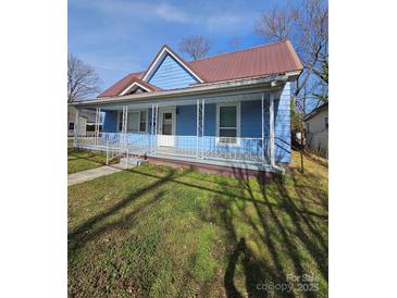 Charming blue home with a metal roof and covered front porch, perfect for relaxing outdoors at 414 S Yadkin Ave, Spencer, NC 28159