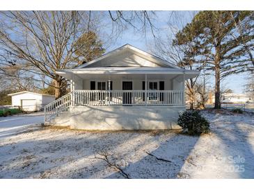 Charming white cottage with a covered porch, freshly landscaped yard, and snowy front lawn at 520 Waddell Dr, Albemarle, NC 28001