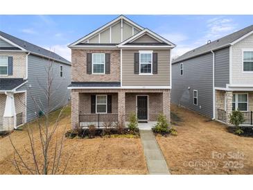 Two-story brick home with a front porch and landscaped yard at 717 Windage Way, Pineville, NC 28134