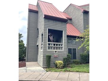 Exterior view of a gray condo building with a red roof and landscaping at 9041 J M Keynes Dr # 10, Charlotte, NC 28262