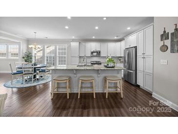 Bright kitchen with white cabinetry, stainless steel appliances, granite countertops, and large kitchen island with seating at 18201 Coulter Pkwy, Cornelius, NC 28031