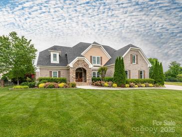 Charming brick home featuring a stone entryway, lush landscaping, and a well-manicured lawn at 3850 Hounslow Ln, Harrisburg, NC 28075