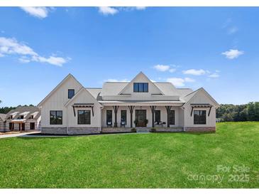 Stunning farmhouse exterior boasts a spacious front porch and beautifully landscaped lawn at 114 Quail Ridge Dr, Mooresville, NC 28117