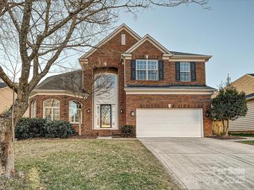 Brick two-story house with a three-car garage and manicured lawn at 12434 Kemerton Ln, Huntersville, NC 28078