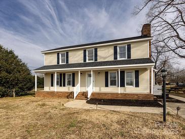 Two-story house with beige vinyl siding, dark shutters, and a brick foundation at 509 Baucom Deese Rd, Monroe, NC 28110