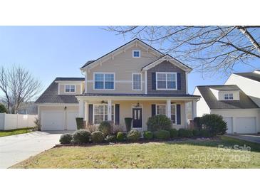 Two-story house with beige siding, two-car garage, and landscaping at 9806 Penn Station St, Cornelius, NC 28031