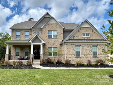 Charming two-story brick home with landscaped yard and welcoming front porch at 14018 Promenade Dr, Huntersville, NC 28078