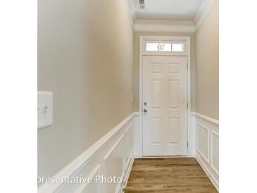 View of the entryway featuring a white front door and decorative trim with wood-look flooring at 4013 Grace Pointe Dr # 102, Wesley Chapel, NC 28079