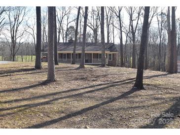 Brick ranch house with a covered porch, nestled among tall trees on a spacious lot at 1008 E Sandy Ridge Rd, Monroe, NC 28112