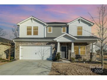 Two-story house with gray siding, stone accents, and a three-car garage at 12613 Stoneybrook Station Pkwy, Huntersville, NC 28078