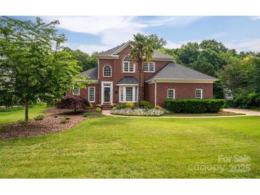 Charming two-story red brick home with well-manicured lawn, mature trees and landscaping, under a sunny sky at 133 Castaway Trl, Mooresville, NC 28117