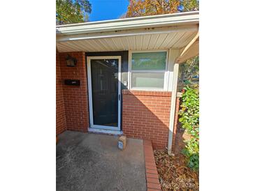 Inviting front door entrance with brick facade and storm door at 3103 Minnesota Rd, Charlotte, NC 28208