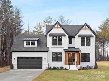 Two-story white brick home with black accents, a gray roof, and a two-car garage at 10517 S Hampton Dr, Charlotte, NC 28227