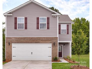 Two-story house with brick and siding, a white garage door, and landscaping at 12152 Lady Bell Dr, Charlotte, NC 28278